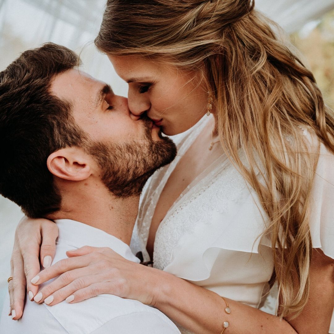 Verliebte Braut küsst Bräutigam und trägt Hochzeitsschmuck von Mia&Martha